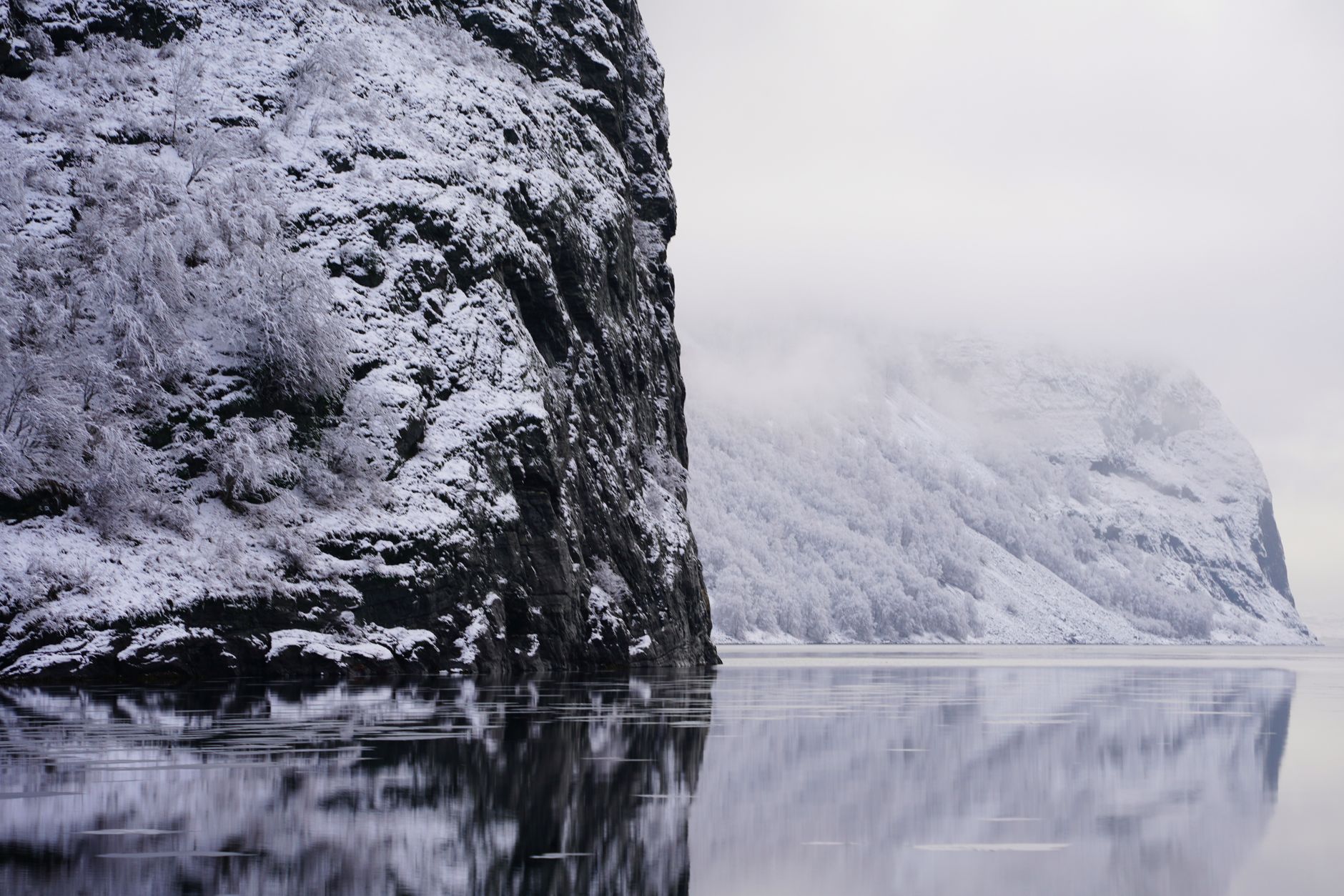 Mist rising through Norwegian fjord cliffside